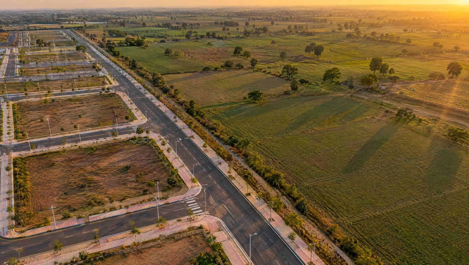 Aerial view of the edge where a new city road grid meets open farmland