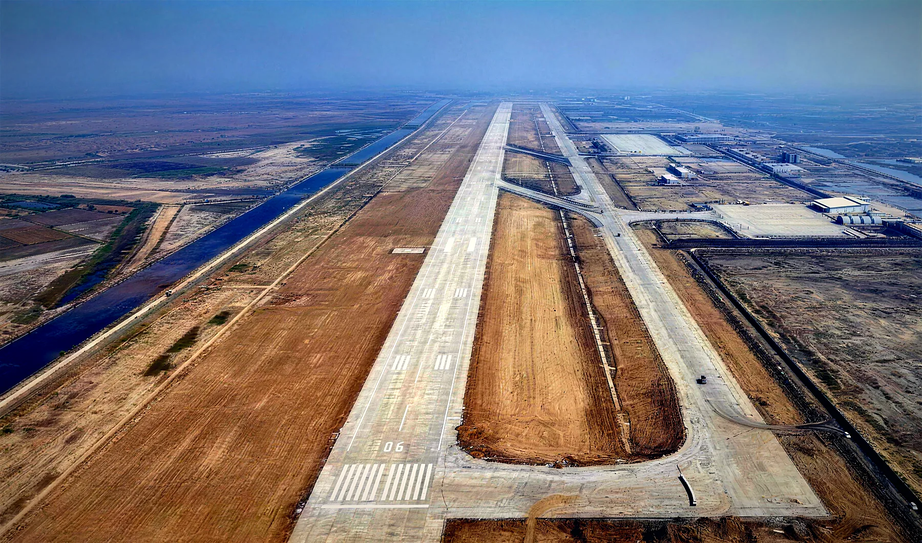 Aerial photo of the Dholera International Airport runway under construction, with taxiways and the apron beside it