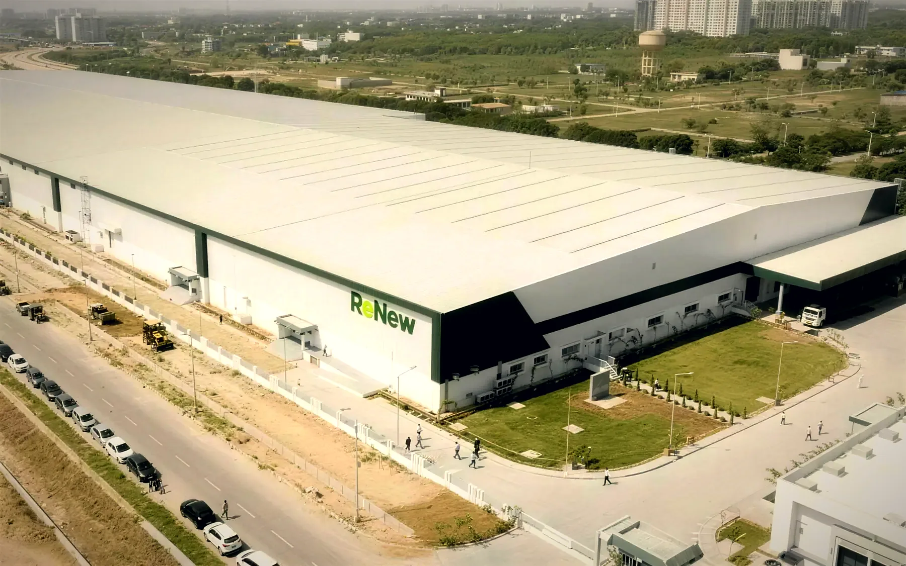 Aerial photo of a large ReNew factory building with a landscaped forecourt beside a new road